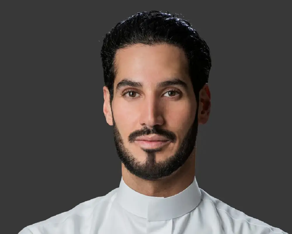 Hassan Jameel headshot with gray background and white collar